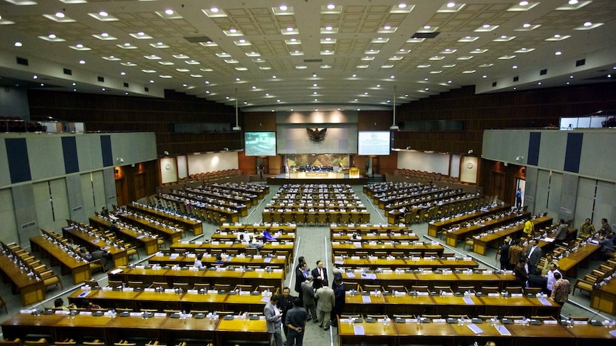 Indonesia's Parliament building in Jakarta. There is a stage at one end with a series of rows of tables.