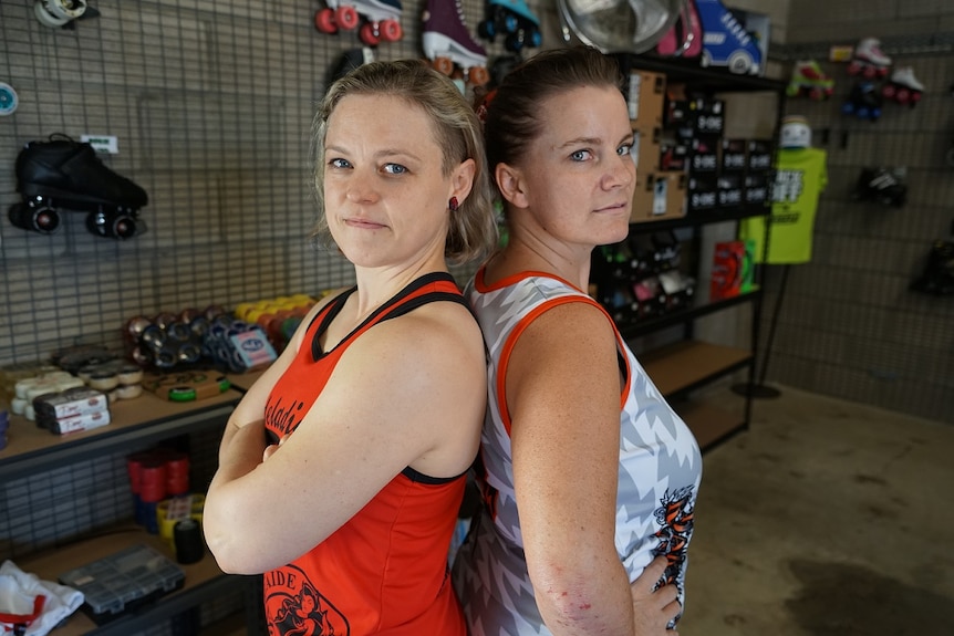 Two women stand back-to-back in a skating shop.