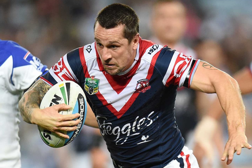 A rugby league player puts his head down and runs with the ball.