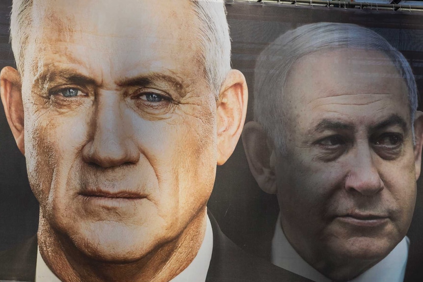 People walk on a bridge below an election poster with the face photos of two men.