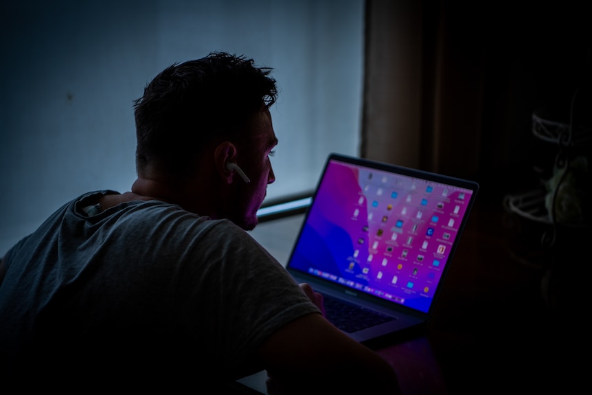 An unidentifiable man looking at a computer screen