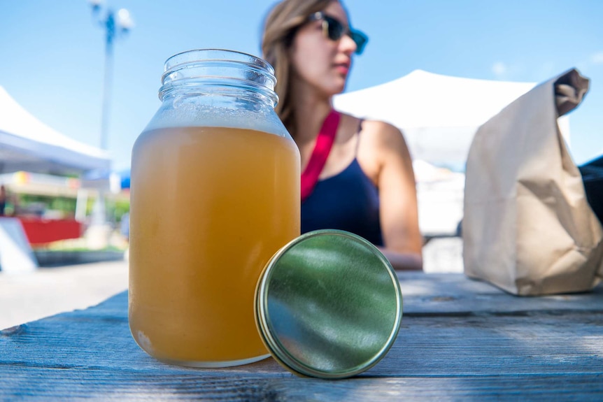 A jar of kombucha on a table at a farmer's market.