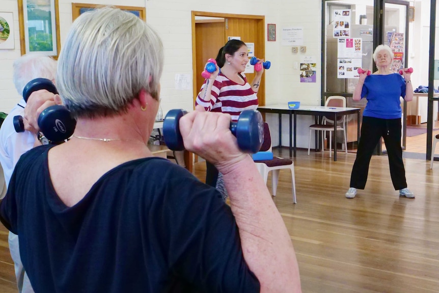 A younger female instructor leads a seniors' exercise program.