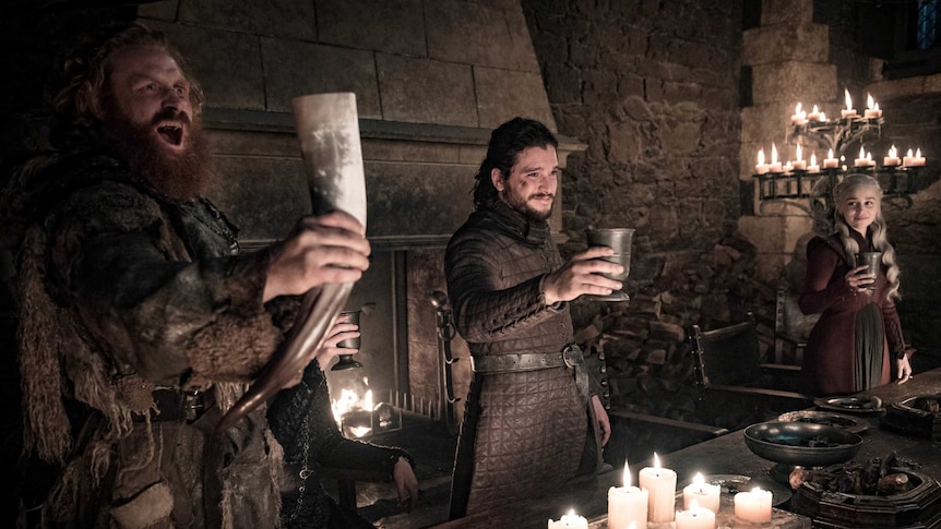 Jon Snow, Tormund Giantsbane and Daenerys Targaryen hold their drinks up in celebration.