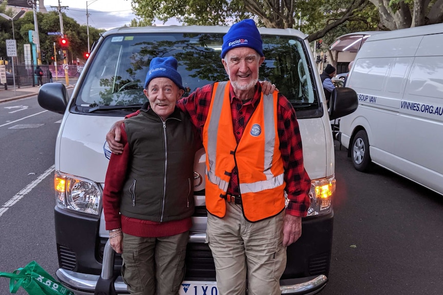 Frank Mullins and Patrick stand smiling at the camera with their arms around each other's shoulders.