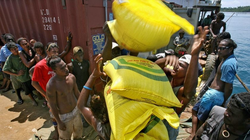 Locals line up to help unload a barge of Red Cross aid in the tsunami-hit town of Gizo.