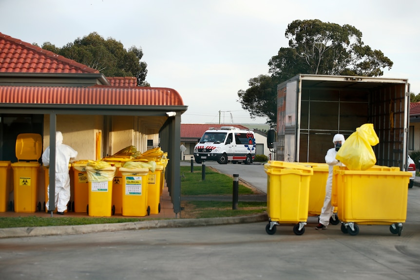 People in hazmat suits removed yellow bags.