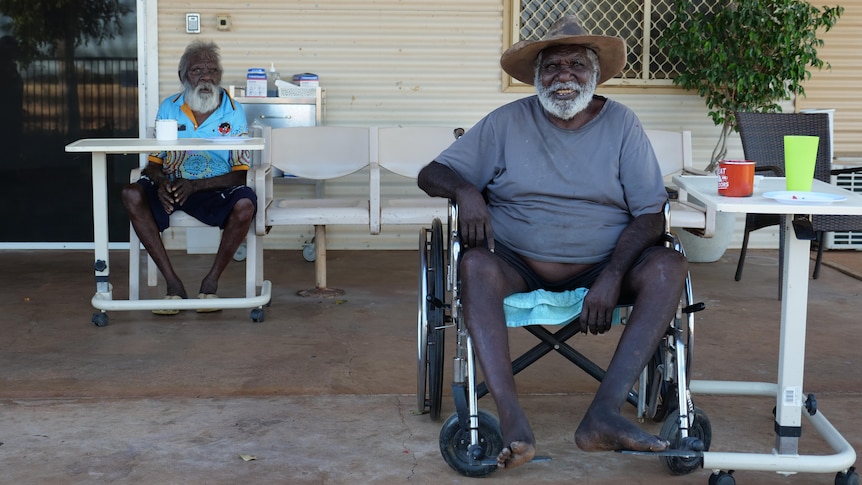 two elderly indigenous men sit at the front porch of the aged care home