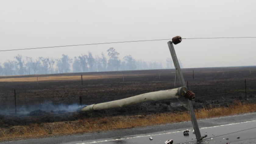 A power pole lies across the Midland Highway after fire raced through the area.