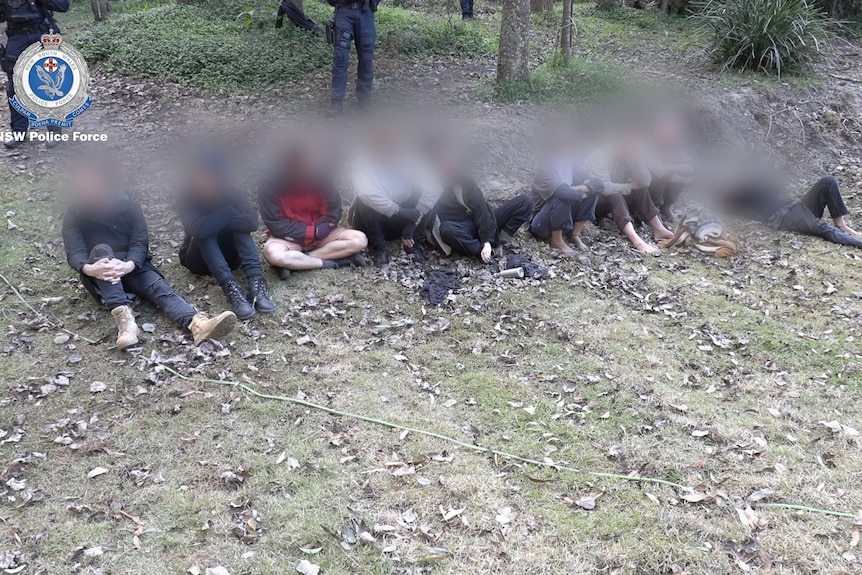 a group of people sitting on the floor after a police operation