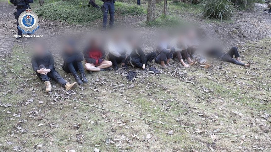 a group of people sitting on the floor after a police operation