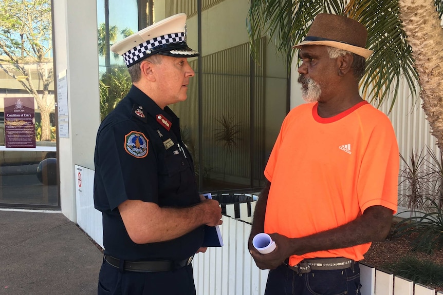 A police officer speaks to an Aboriginal man outside court.