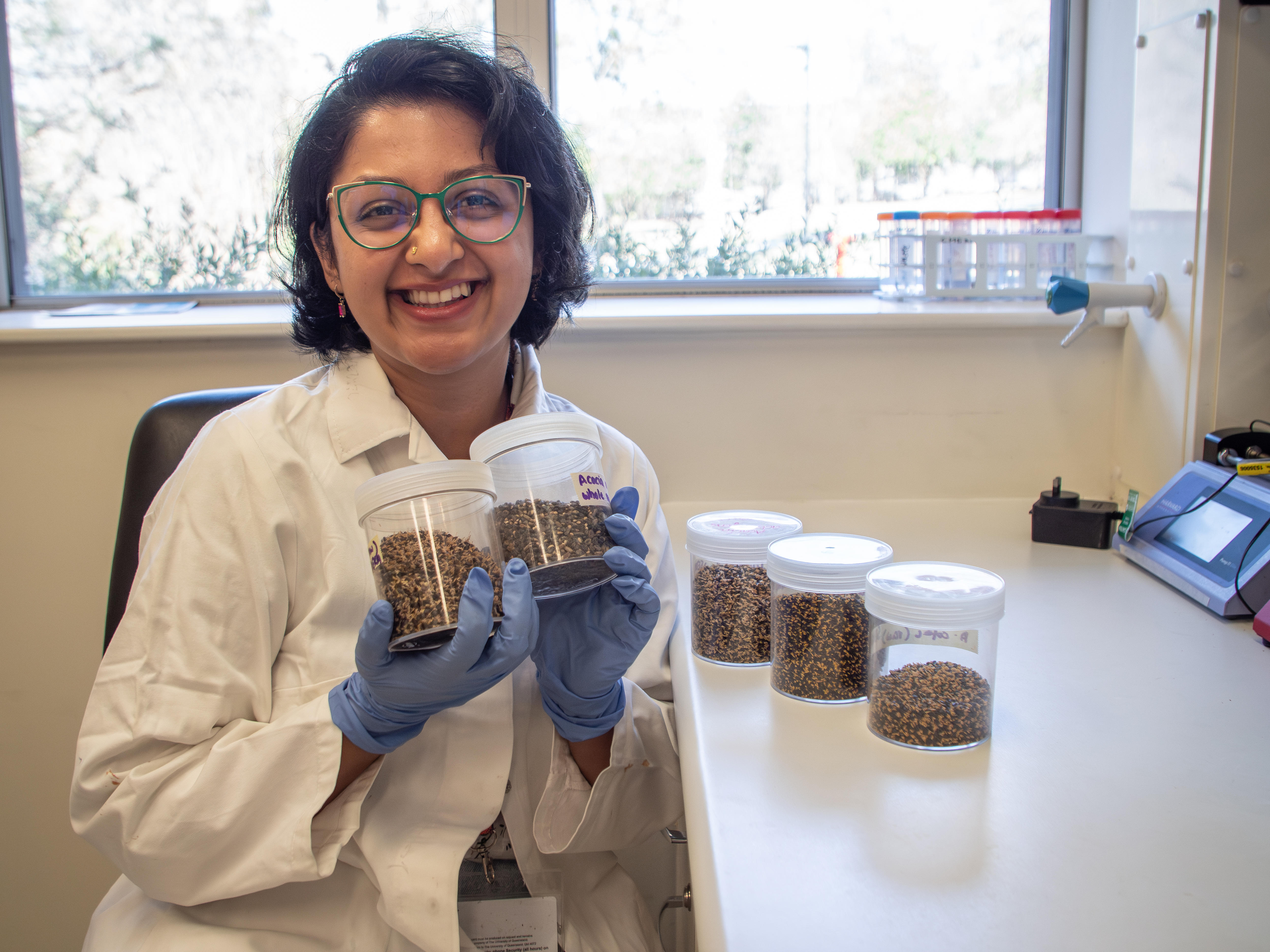 Researcher Sera Susan Jacob holding jars of wattleseed