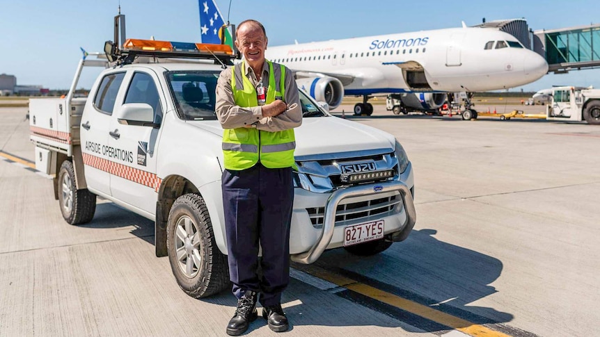Man standing in front of a car and airplane.