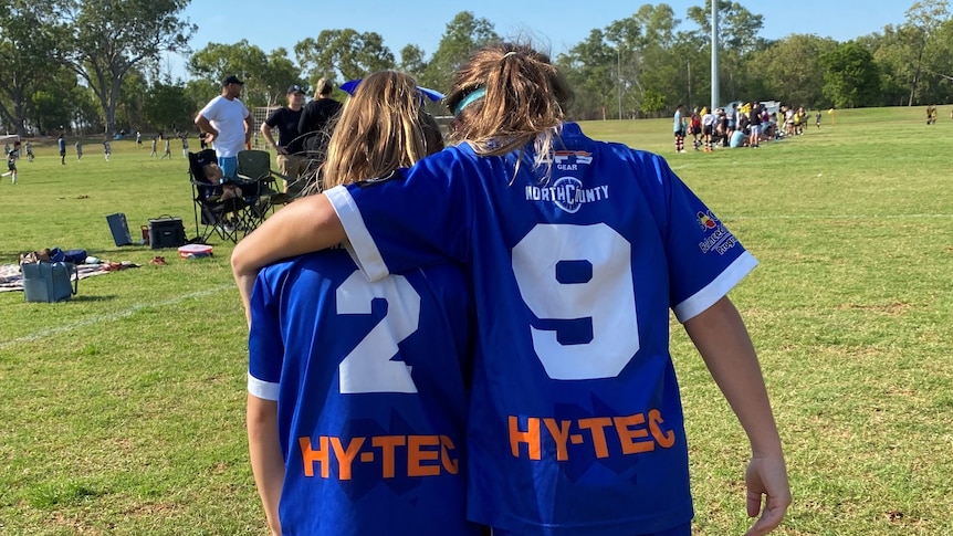Junior girls soccer teammates walk arm-in-arm off the field in Darwin.