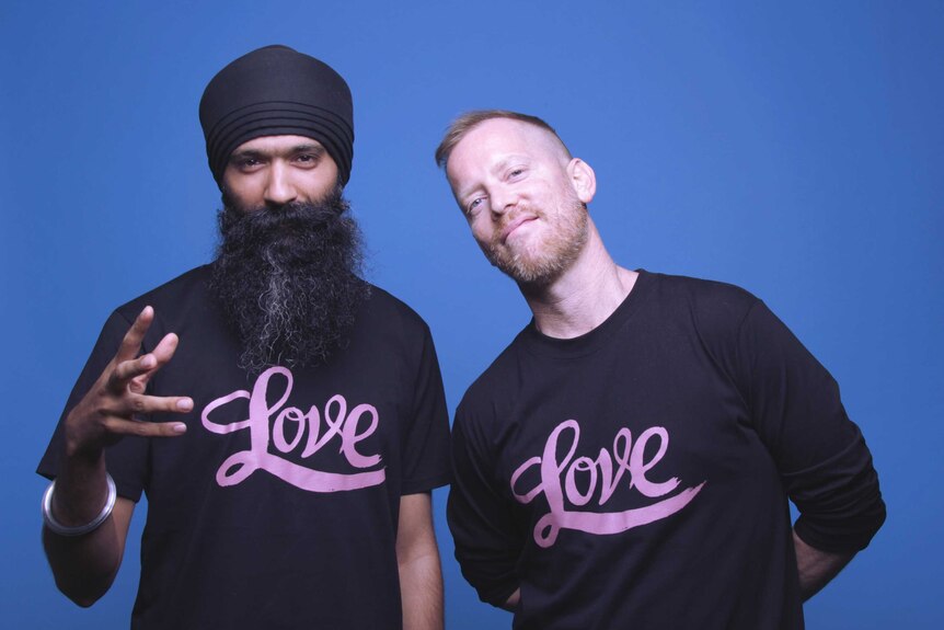 Australian male rappers L-FRESH The LION and Tim Levinson pose in front of a blue background wearing tshirts that say "Love"