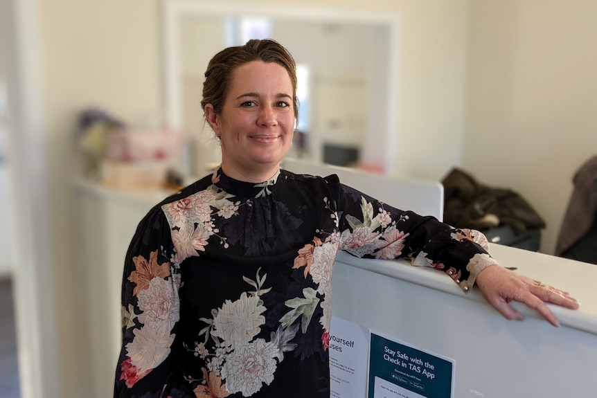 A woman stands next to a counter and smiles at the camera