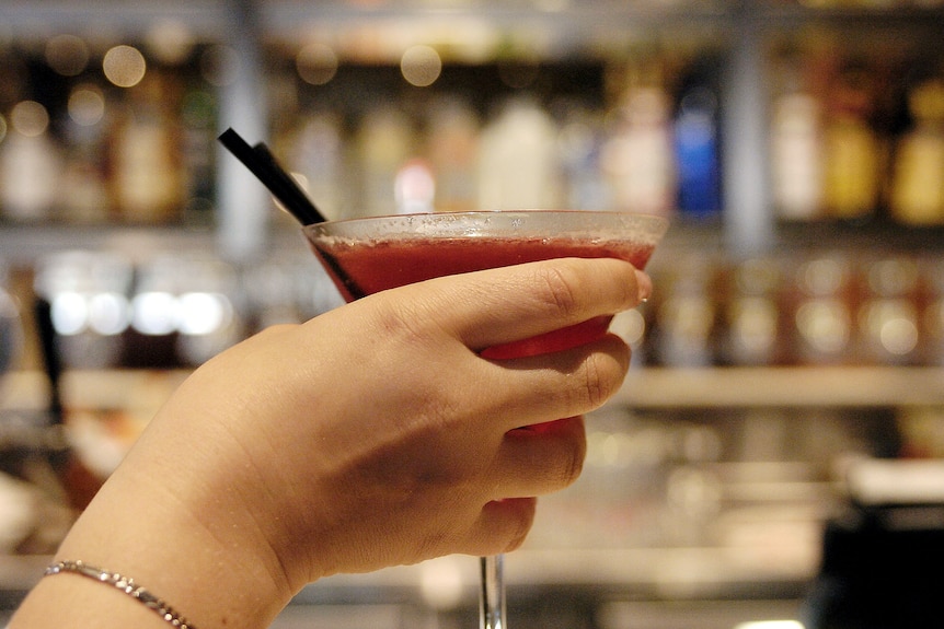 a woman holding a glass full of a cocktail drink