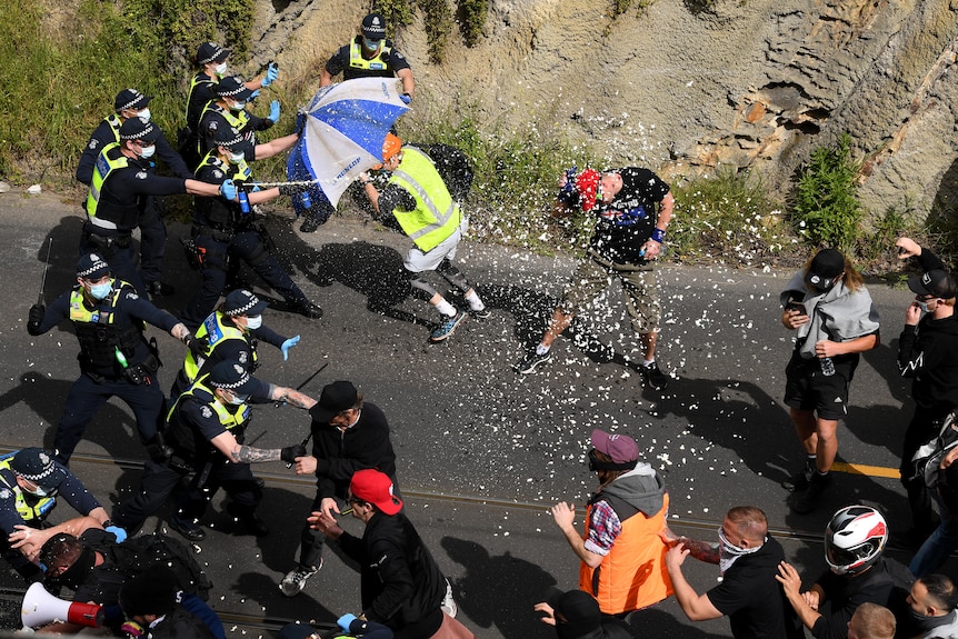 Police use capsicum spray on demonstrators, who are charging at them.