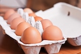A dozen eggs sitting in a carton