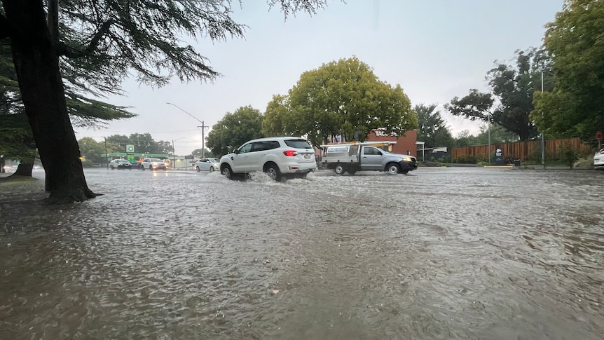 Water across a suburban street with cars driving through