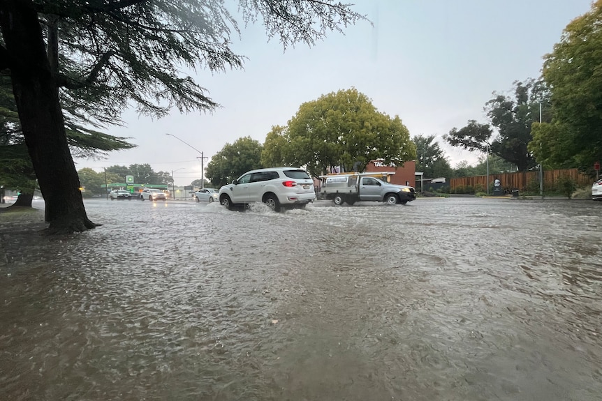 Water across a suburban street with cars driving through