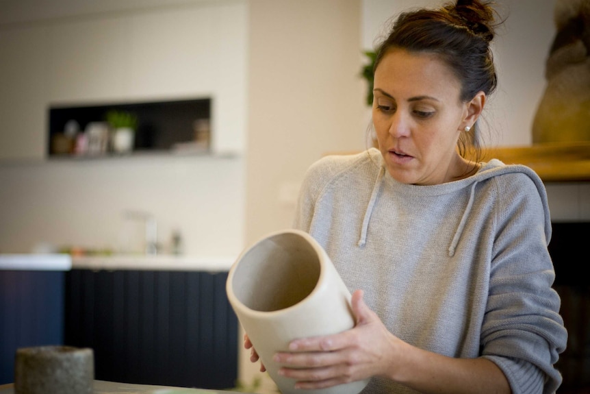 Ali Fairbairn shapes a large pottery vase on the kitchen table in her home.