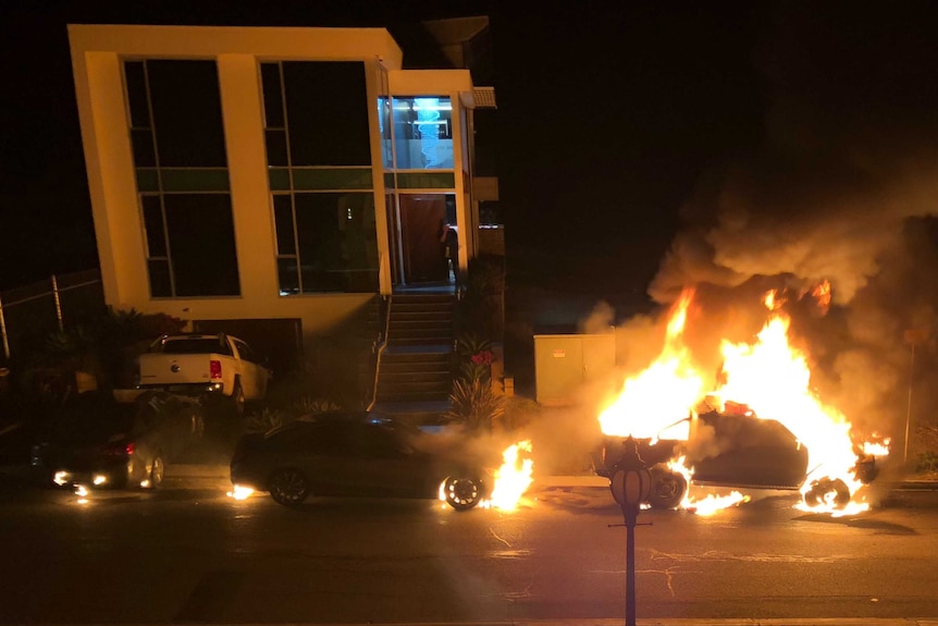 a two storey house with three cars on fire out the front