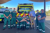 Paramedics and politician standing in front of ambulance