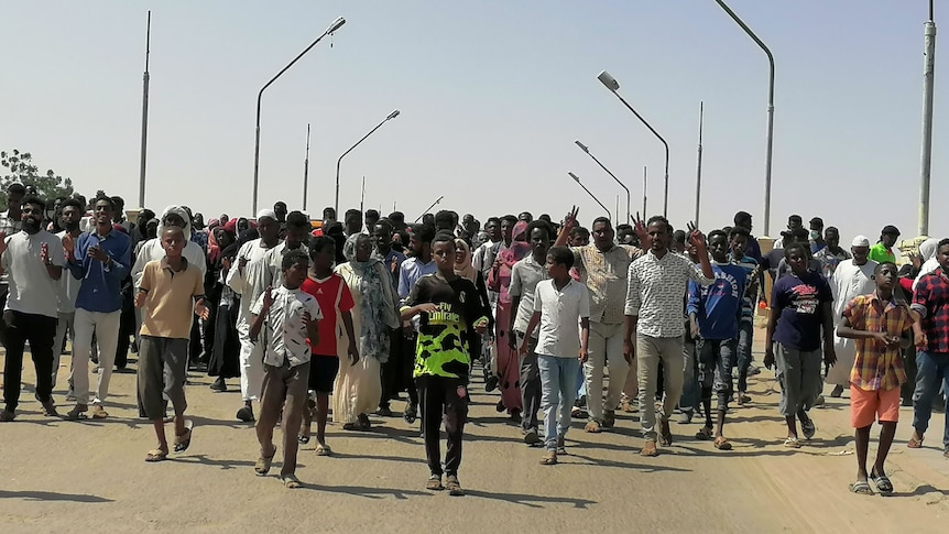 Protesters march down a street chanting slogans against the military coup, October 27, 2021.