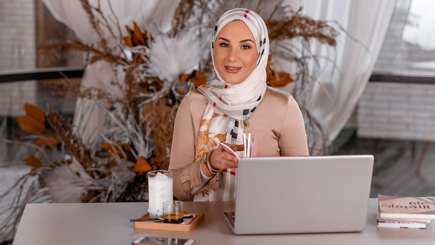 A womn sitting with a laptop open on her desk