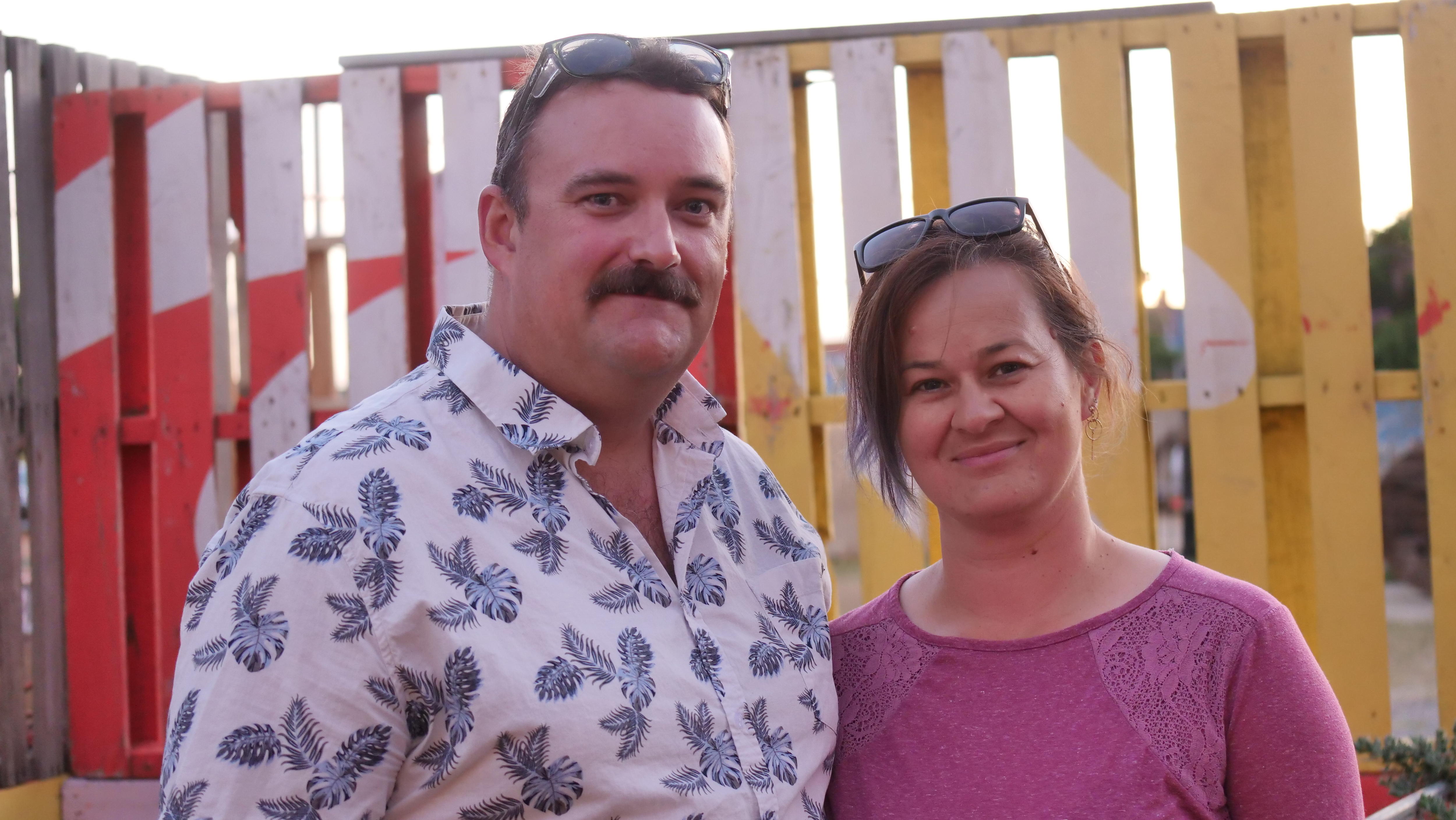 Una pareja de cabello castaño sonríe a la cámara. 
