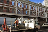 Worker in truck removes building struts.