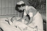 A nurse leaning over a young male patient wearing callipers.