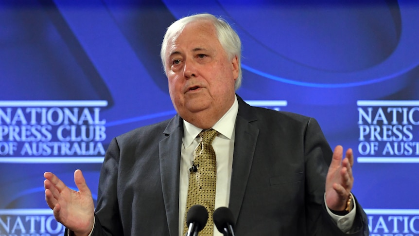Clive speaks at a podium in front of a blue National Press Club of Australia backdrop and gestures with his hands.