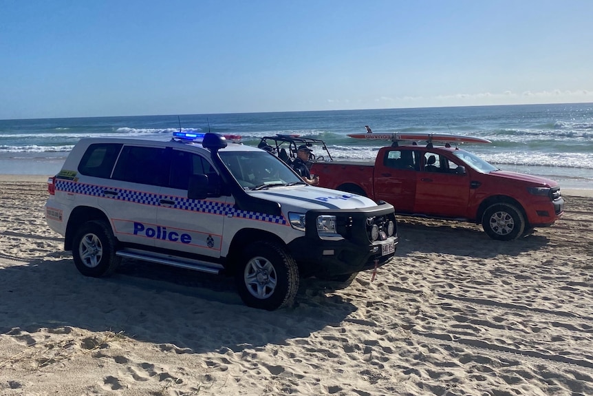 Police and lifeguard vehicles on a beach.