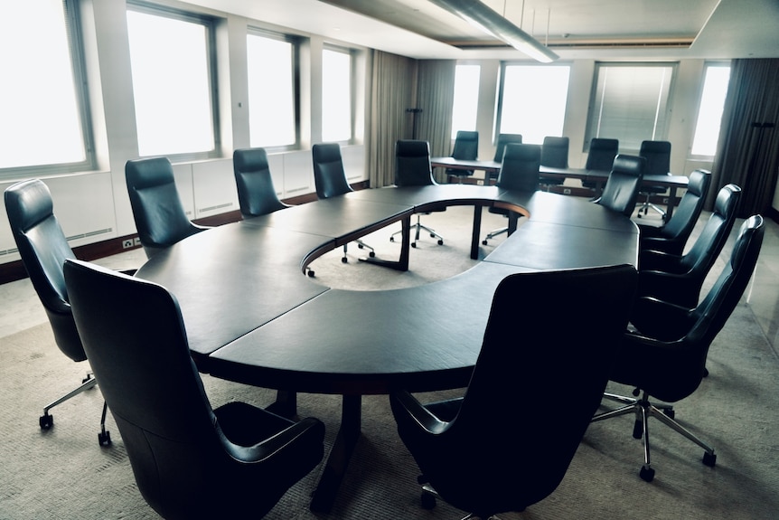 A board table surrounded by chairs in an empty boardroom.