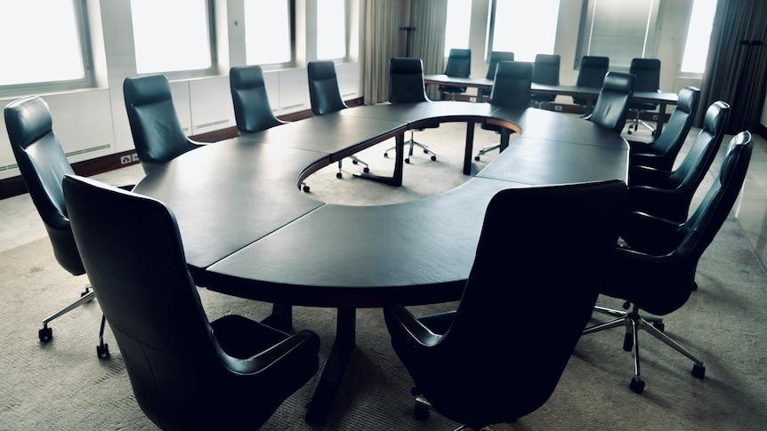 A board table surrounded by chairs in an empty boardroom.