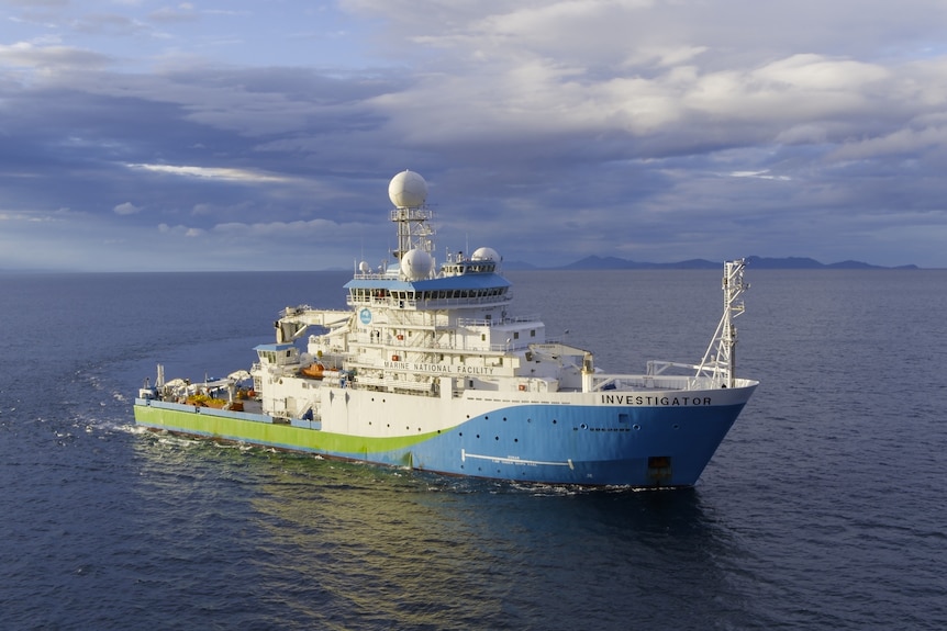 Large blue and green survey ship in ocean water.