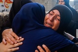 Women weep as they embrace each other in a Gaza street