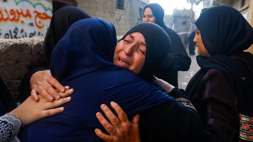 Women weep as they embrace each other in a Gaza street
