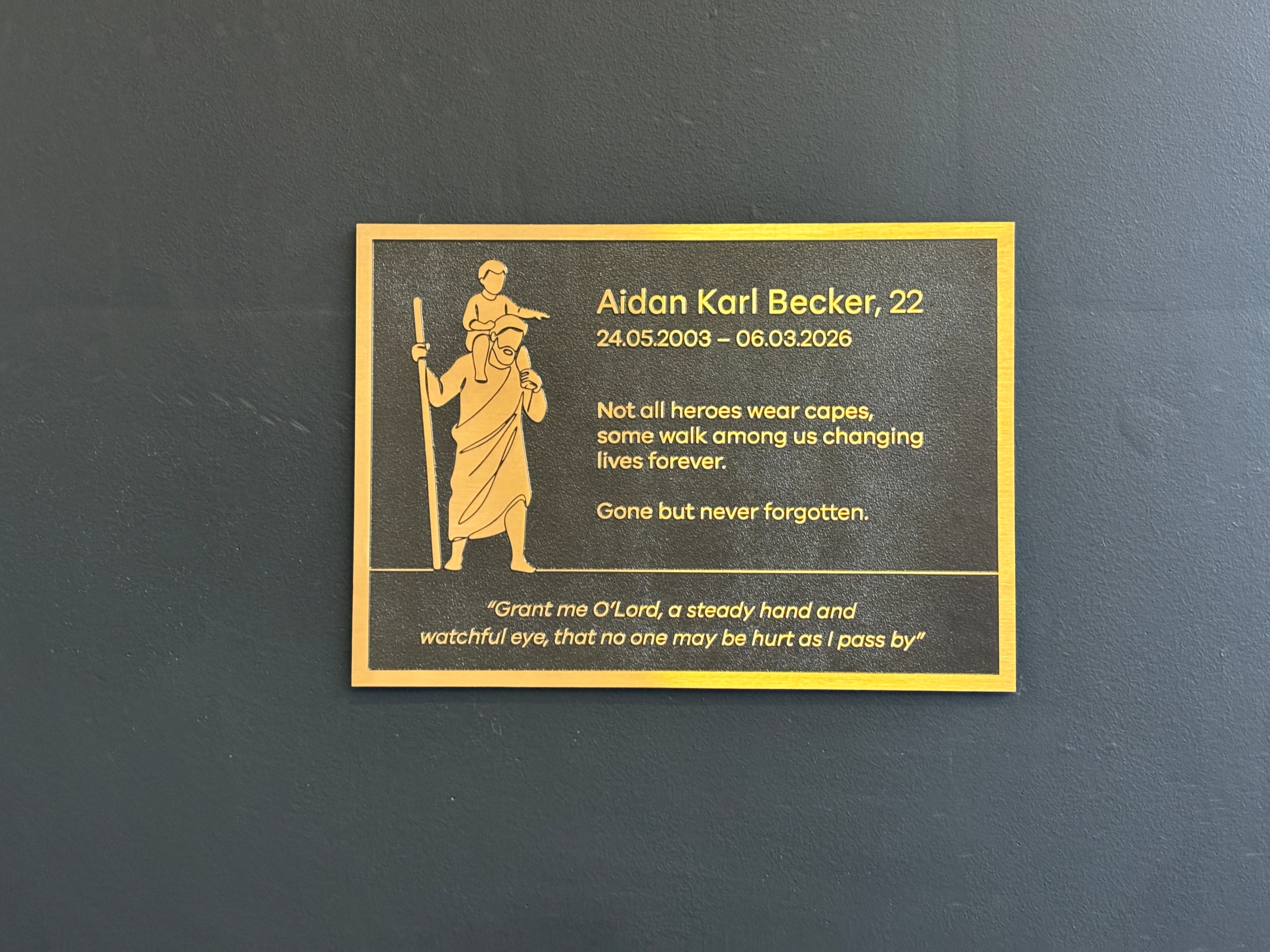 A brown and bold plaque showing a young boy on the shoulders of a woman