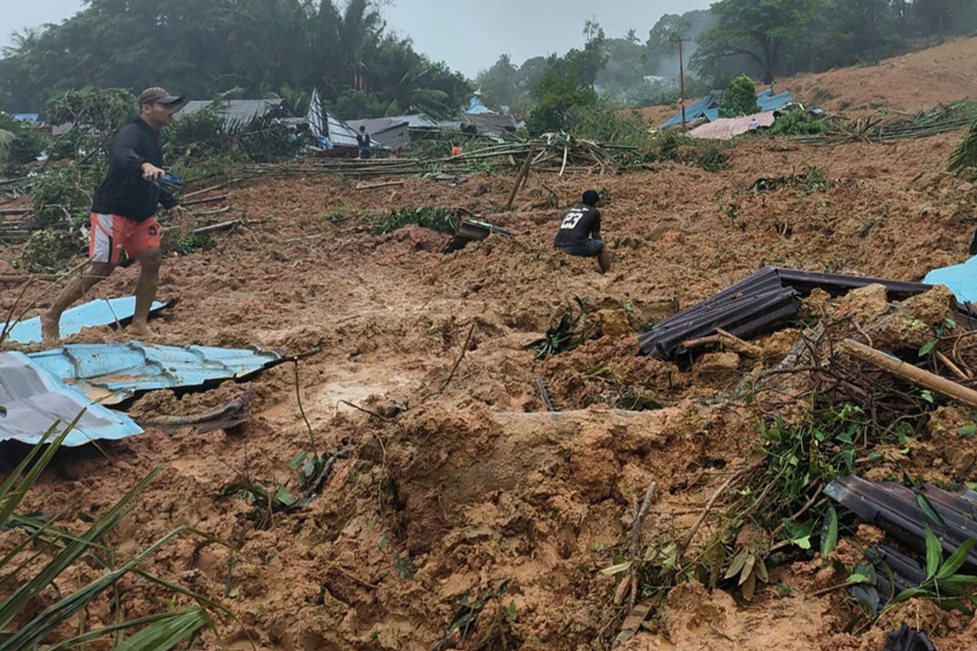 People inspect the site of a landslide.