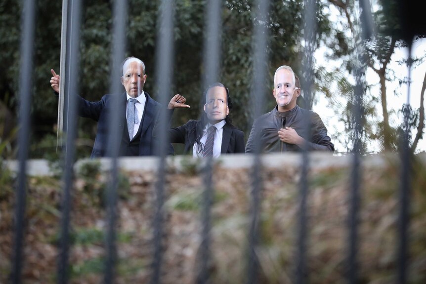Three people are wearing face masks of Peter Dutton, Tony Abbott and Malcolm Turnbull