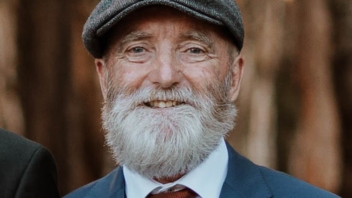 A man wearing a suit with a grey beard
