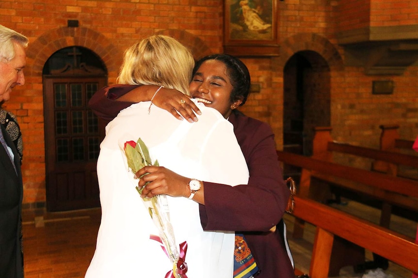 Student Soumiga Gopalakrishnan smiles as she is hugged by a wellwisher at her graduation mass in Brisbane.