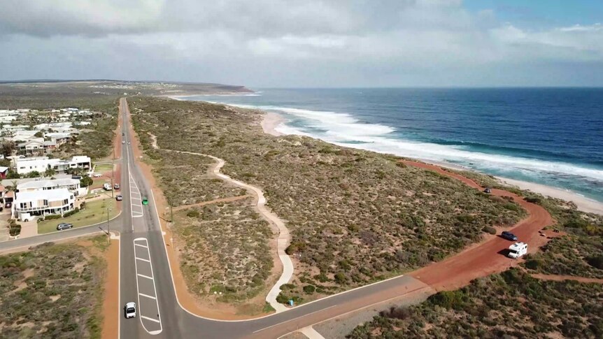 An aerial drone photo of a regional coastline, with red dirt and shrubs meeting cliffs and ocean.