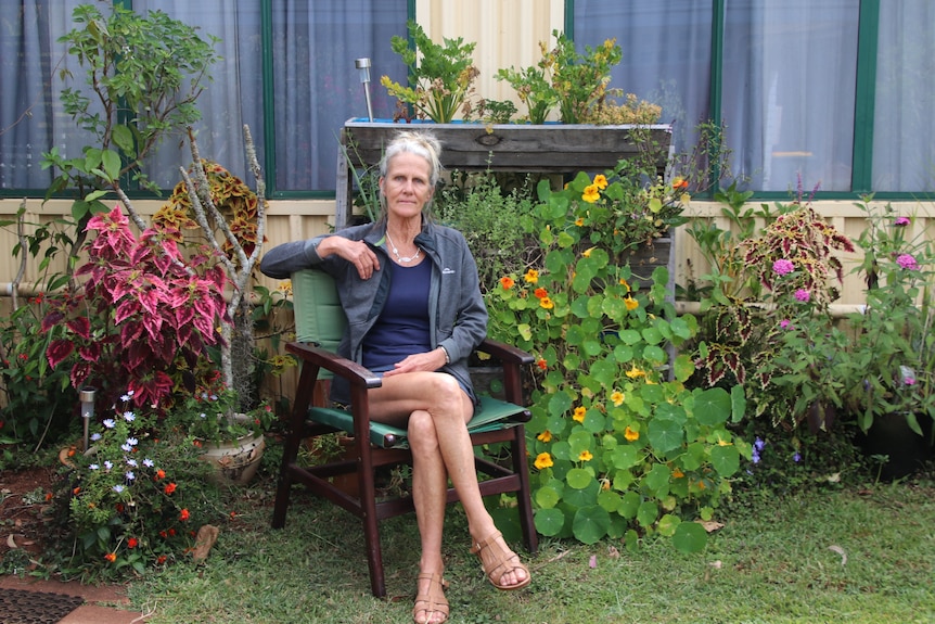 Jenny Sadar sitting on a chair in her her garden outside of her caravan 