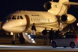 People walk off a plane carrying three Iranian-Americans who left Tehran under a prisoner swap.