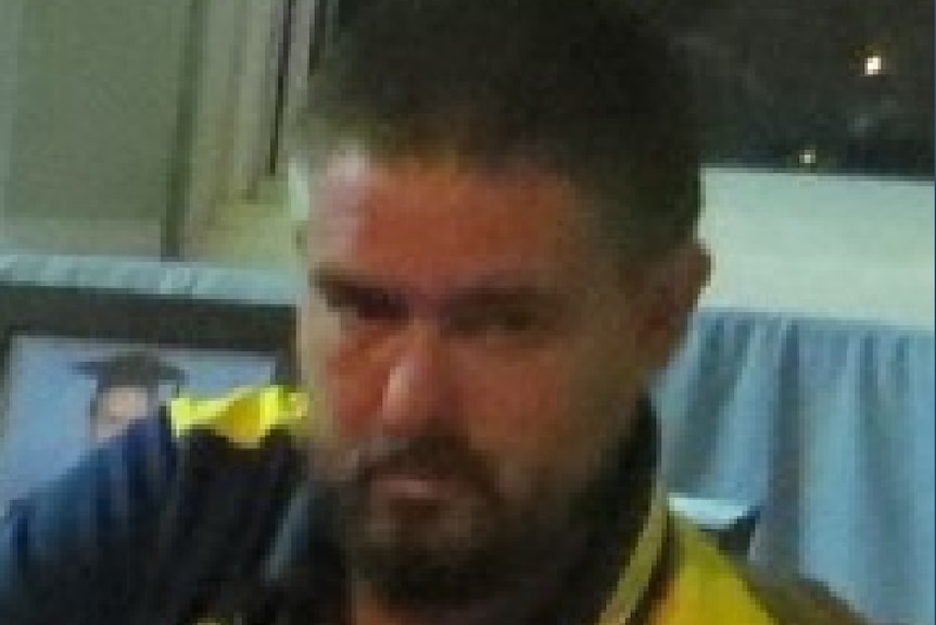 A man with black hair and a beard wearing a sports polo top